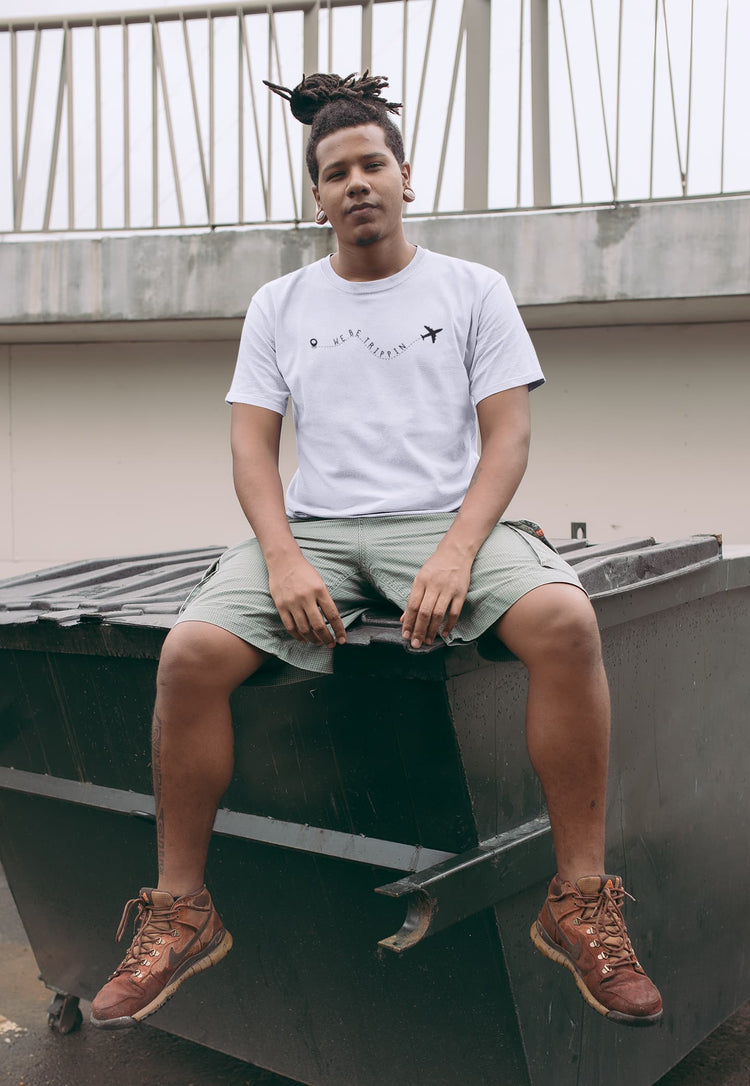 Person sitting on a rooftop wearing a white t-shirt and green shorts.
