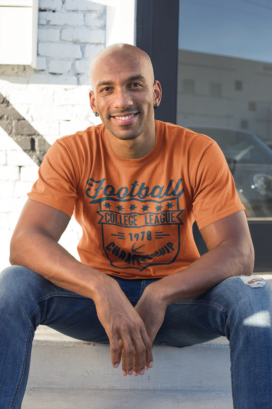Man wearing an orange t-shirt with text sitting on steps.