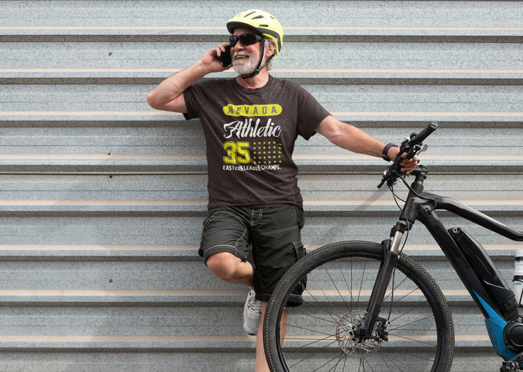 Man with a bicycle wearing a helmet and sunglasses, leaning against a metal wall.