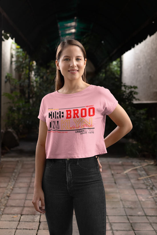 Woman wearing a pink t-shirt with text standing outdoors.
