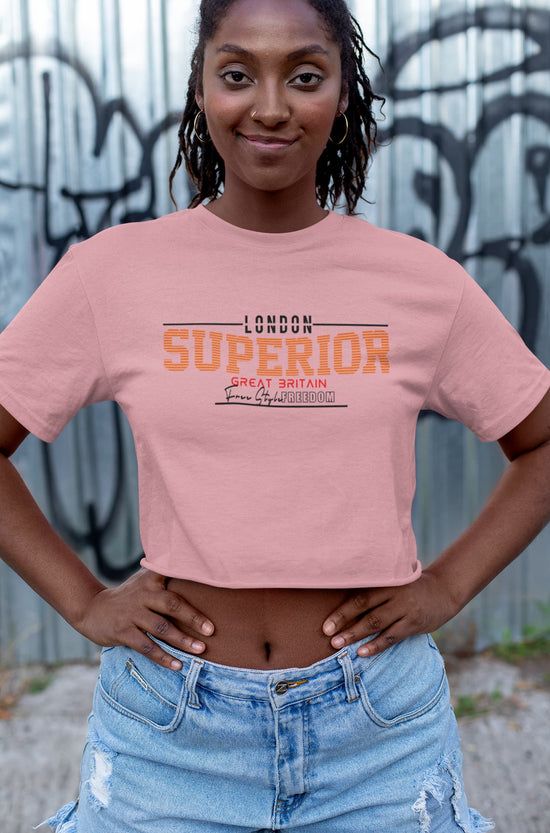 Person wearing a pink crop top with text, standing against a graffiti-covered wall.