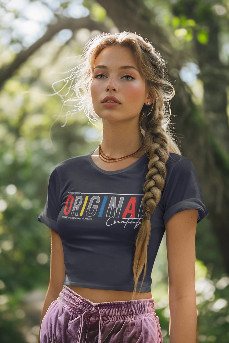 Woman wearing a dark blue t-shirt with colorful text, standing outdoors with greenery in the background