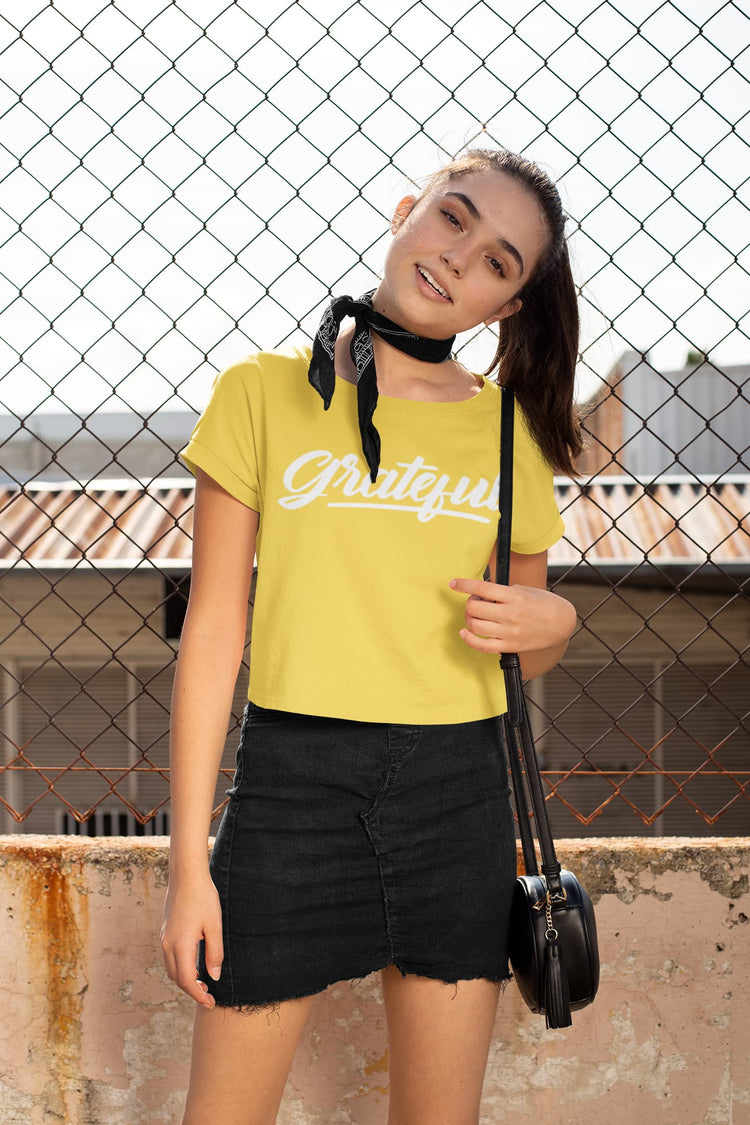 Person wearing a yellow t-shirt with text and black shorts standing against a chain-link fence.
