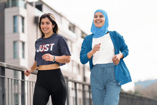 Two women jogging outdoors with a modern building in the background