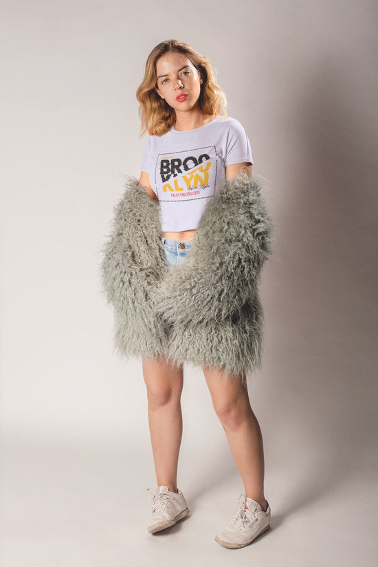 Person wearing a fluffy gray skirt and white sneakers on a plain background