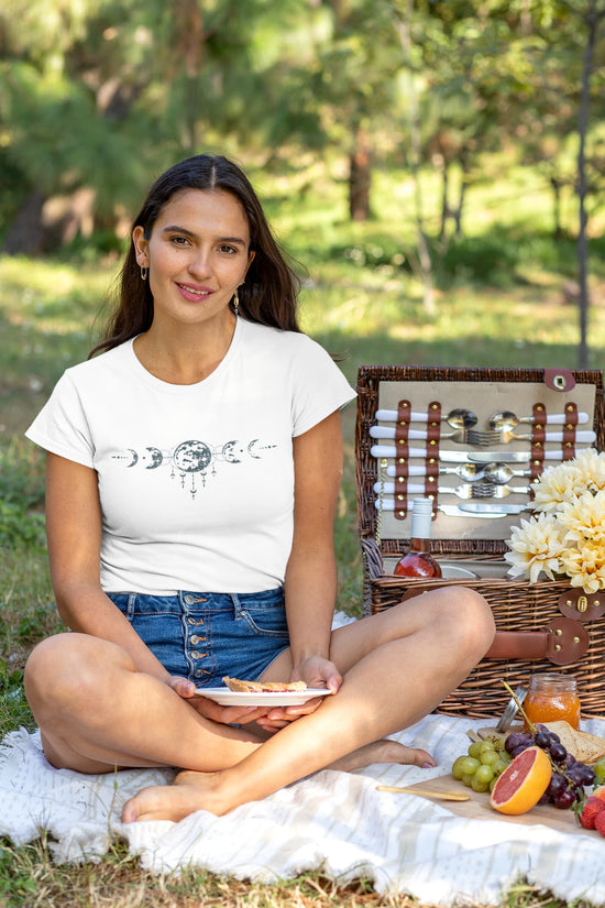 Woman sitting on a picnic blanket with a basket and food in a park