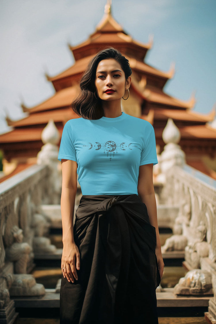 Woman wearing a blue t-shirt with a graphic design in front of a temple.