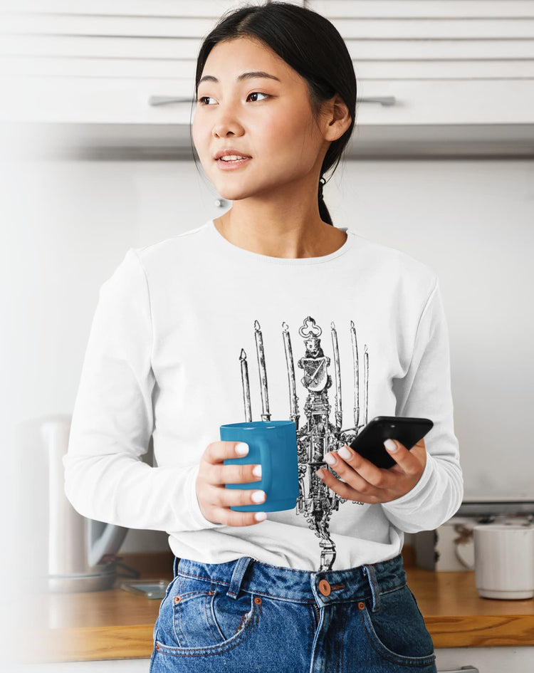 Person wearing a white sweatshirt with a graphic design, holding a blue mug and a phone in a kitchen.