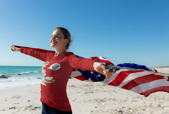 Person holding an American flag on a beach with a clear blue sky