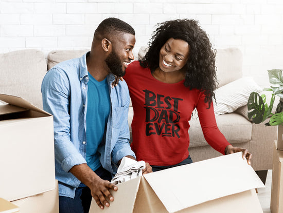 Man and woman unpacking boxes in a living room, with the woman wearing a &