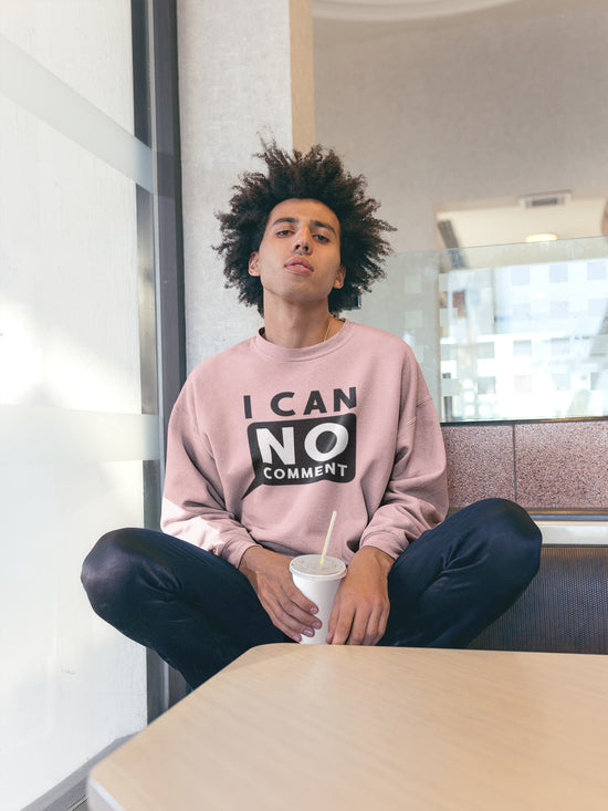 Person wearing a pink sweatshirt with text sitting in an indoor setting.