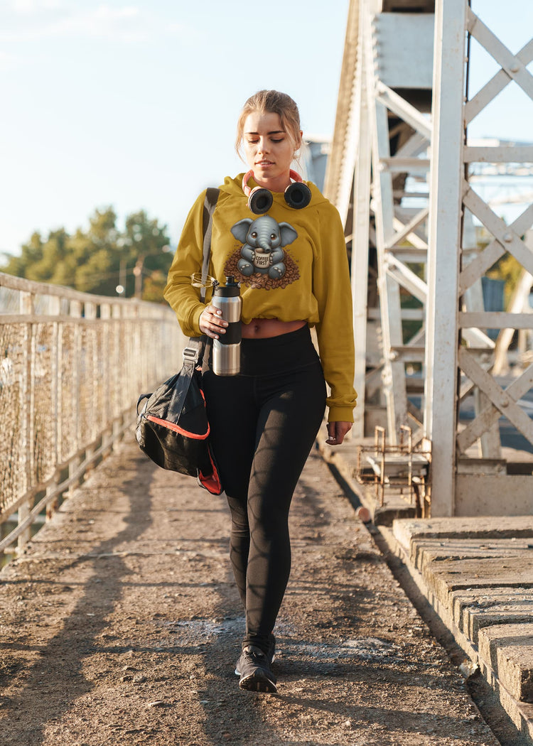 Person walking on a bridge wearing a yellow hoodie with a graphic design, holding a water bottle and a bag.