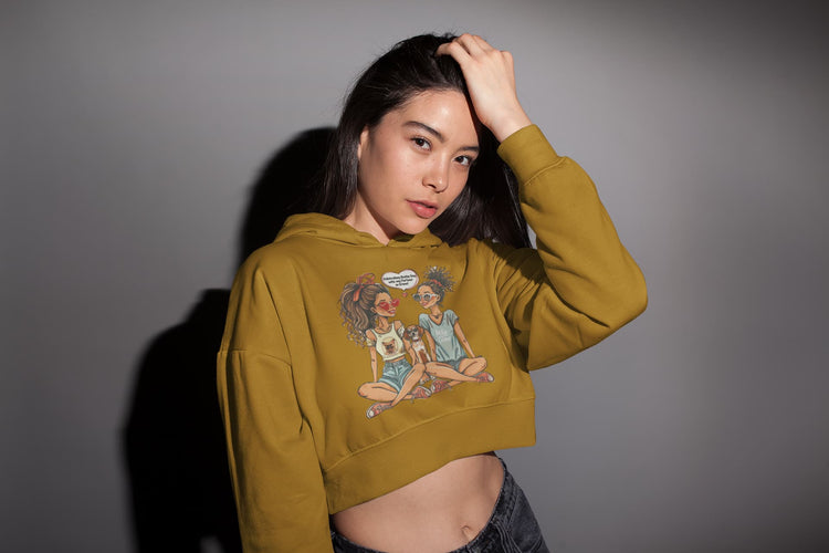 Woman wearing a mustard yellow hoodie with a graphic design on a gray background