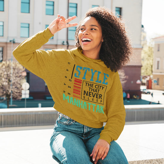 Woman wearing a mustard yellow sweatshirt with text, sitting outdoors.