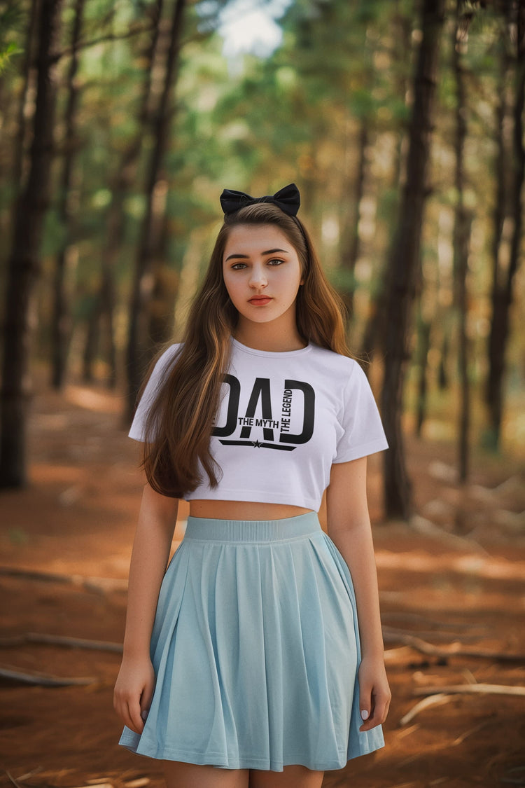 Woman wearing a white crop top with text and a light blue skirt in a forest setting