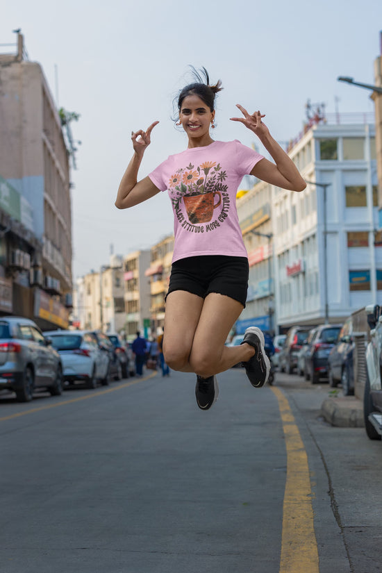 Woman in a pink t-shirt and black shorts jumping on a city street.