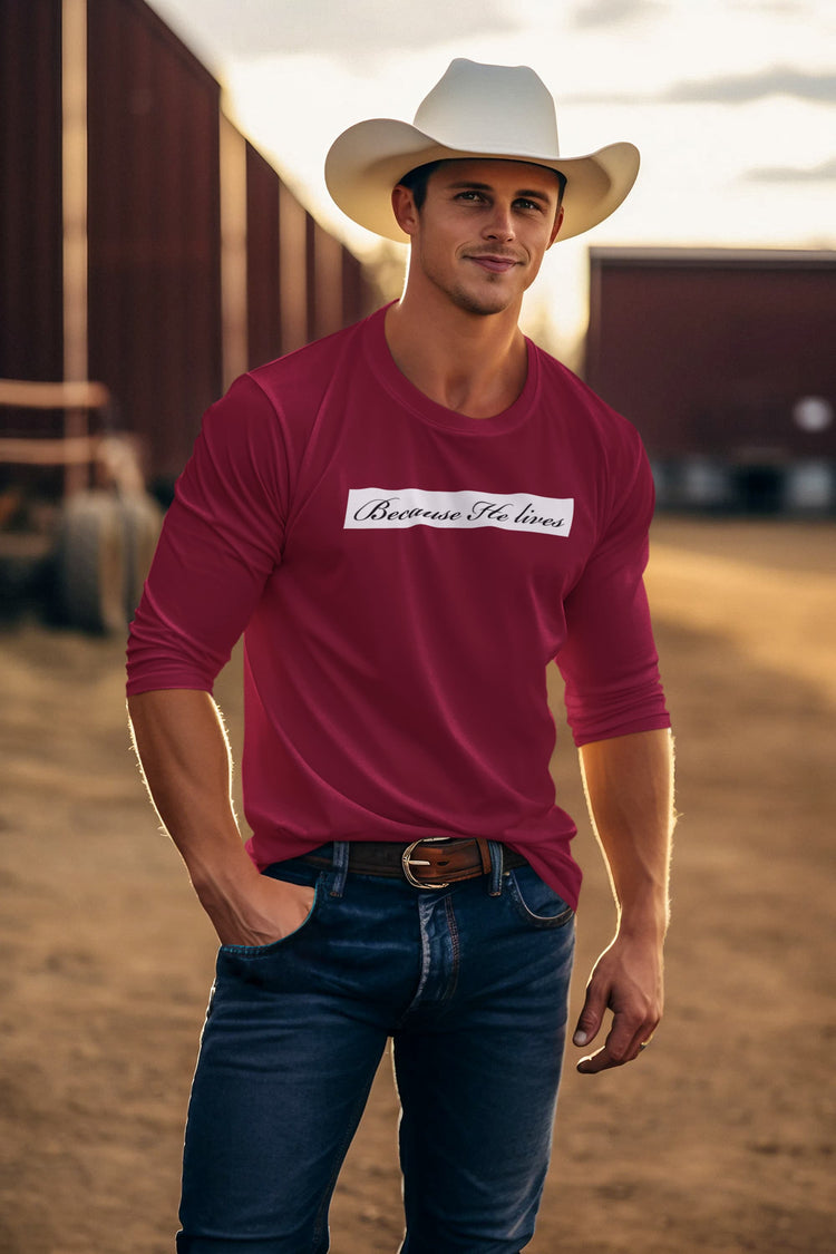 Man wearing a red shirt with text and a cowboy hat in a rural setting