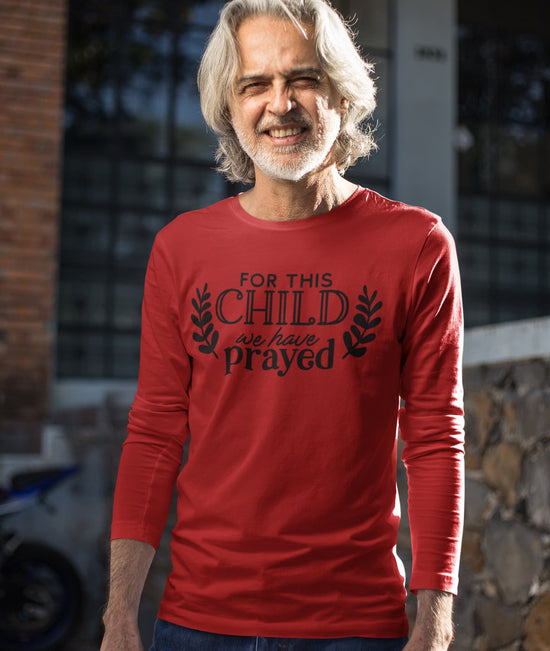 Man wearing a red long-sleeve shirt with text standing outdoors.