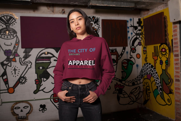 Person wearing a maroon hoodie with text in an urban setting with colorful wall art.