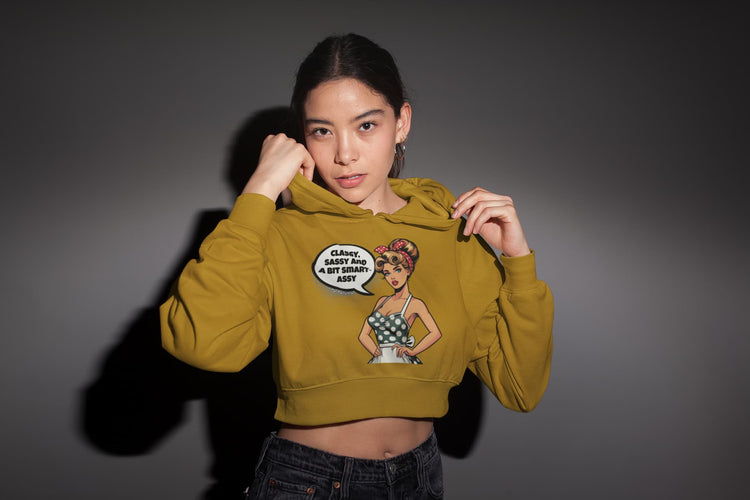 Woman wearing a mustard yellow hoodie with a graphic design on a gray background
