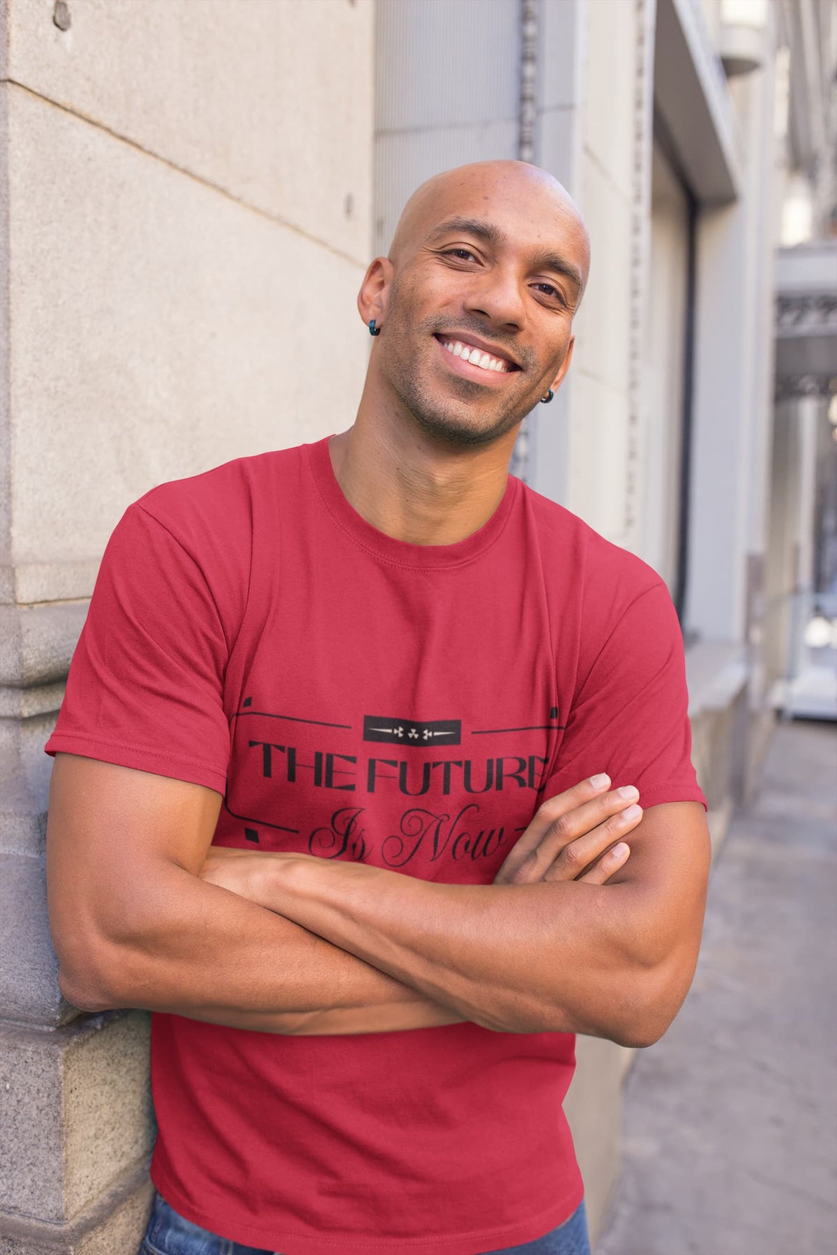 Man wearing a red t-shirt with text, standing against a building wall.