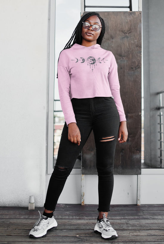 Woman wearing a pink cropped hoodie and black leggings standing on a wooden deck.