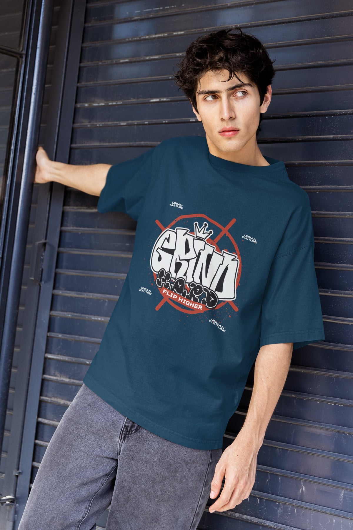 Person wearing a blue t-shirt with a graphic design against a metallic background