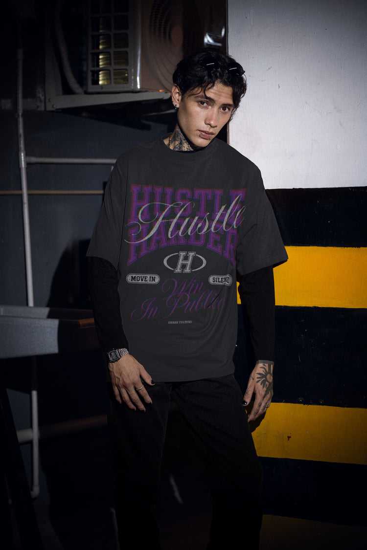 Person wearing a black t-shirt with text and graphics, standing against a striped wall.