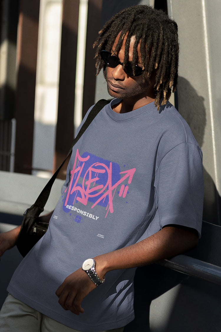 Person wearing a blue t-shirt with pink and red graphics, sitting outdoors.