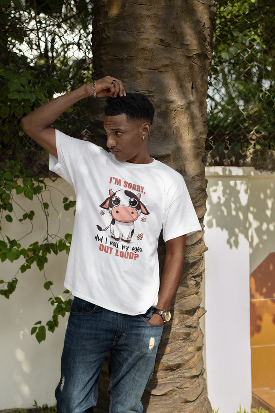Person wearing a white t-shirt with a cow graphic and text, standing next to a tree.