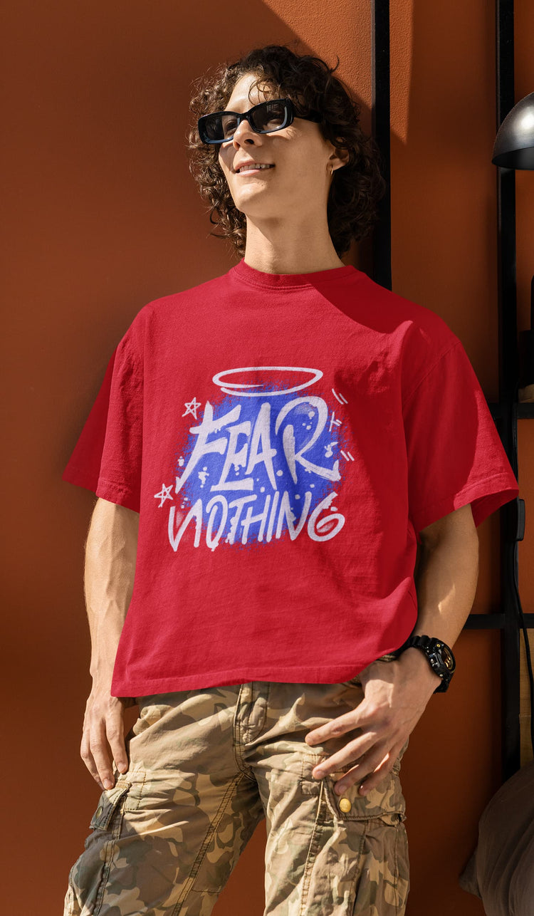 Person wearing a red t-shirt with graphic design and text, standing against an orange wall.