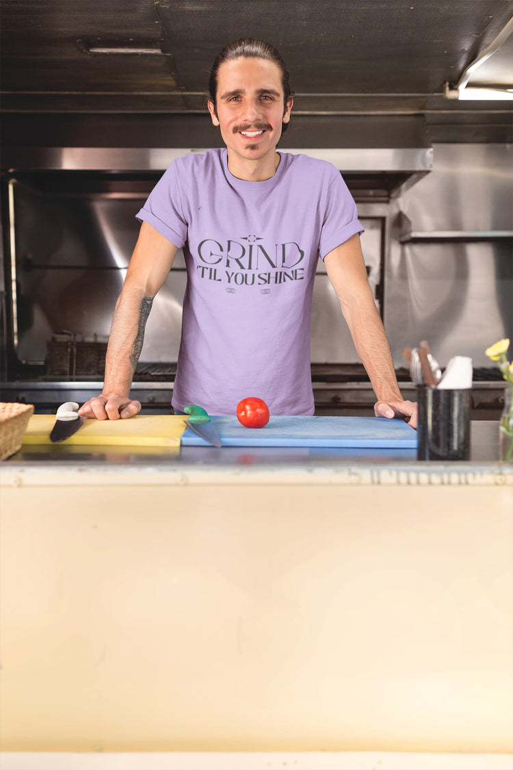 Person wearing a purple t-shirt with text in a kitchen setting