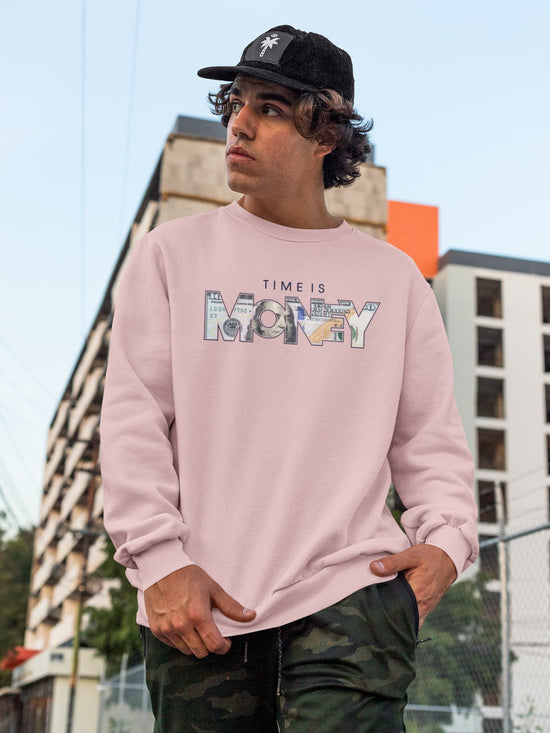 Person wearing a pink sweatshirt with text, standing outdoors with buildings in the background