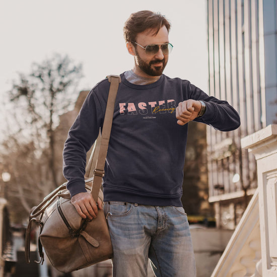 Man wearing a navy sweatshirt with text, holding a brown bag, and checking his watch outdoors.