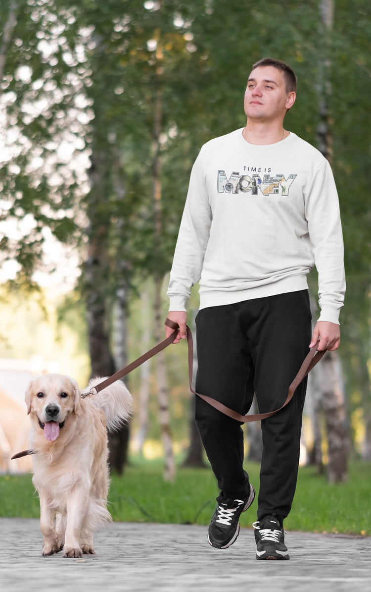 Man walking a dog on a leash in a park with trees in the background