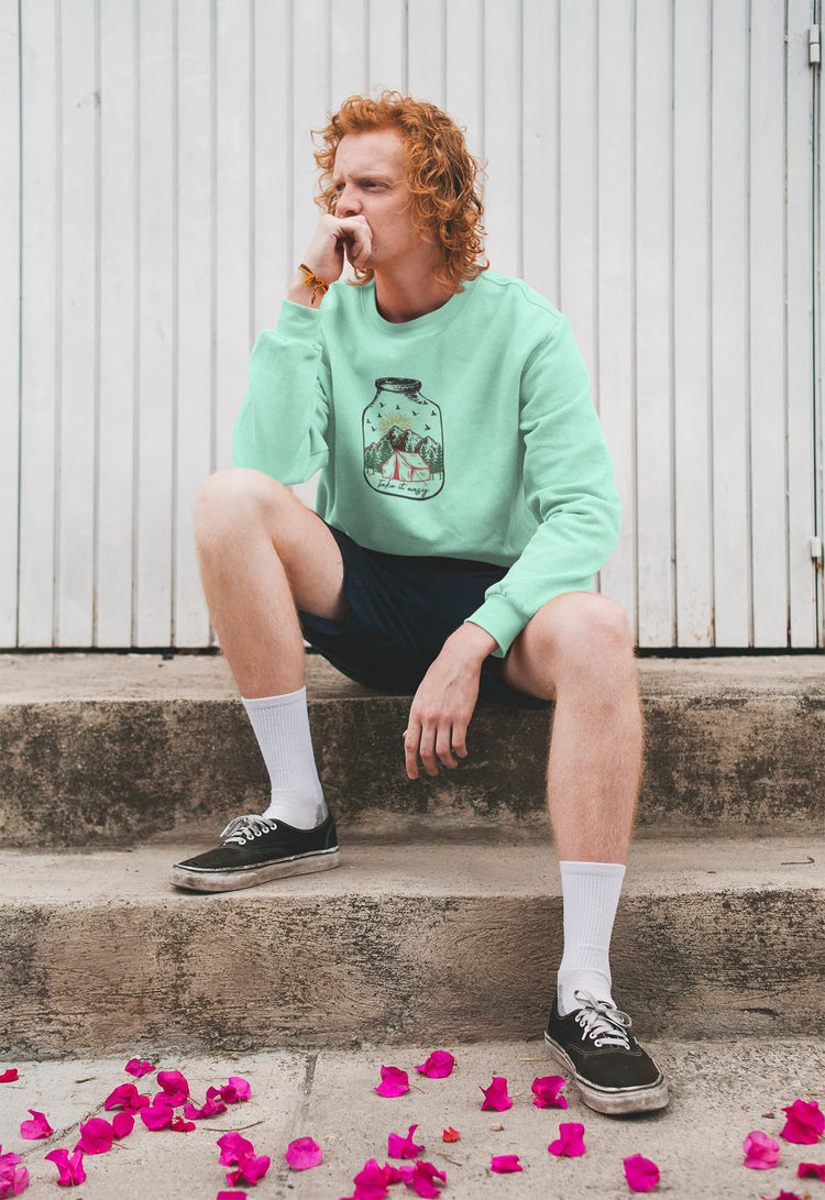 Person wearing a light green sweatshirt with a design, sitting on steps with pink petals around.