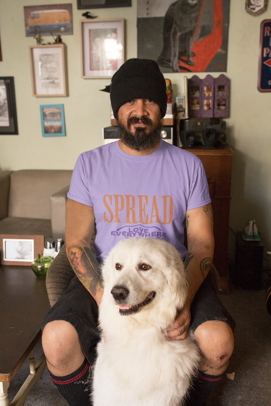 Man sitting with a white dog in a room with framed pictures on the wall.
