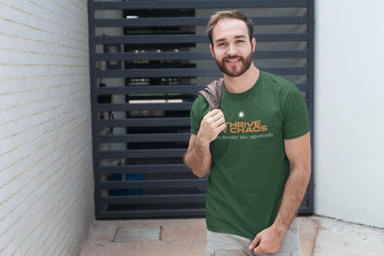 Man wearing a green t-shirt with a logo and text, standing against a brick wall.