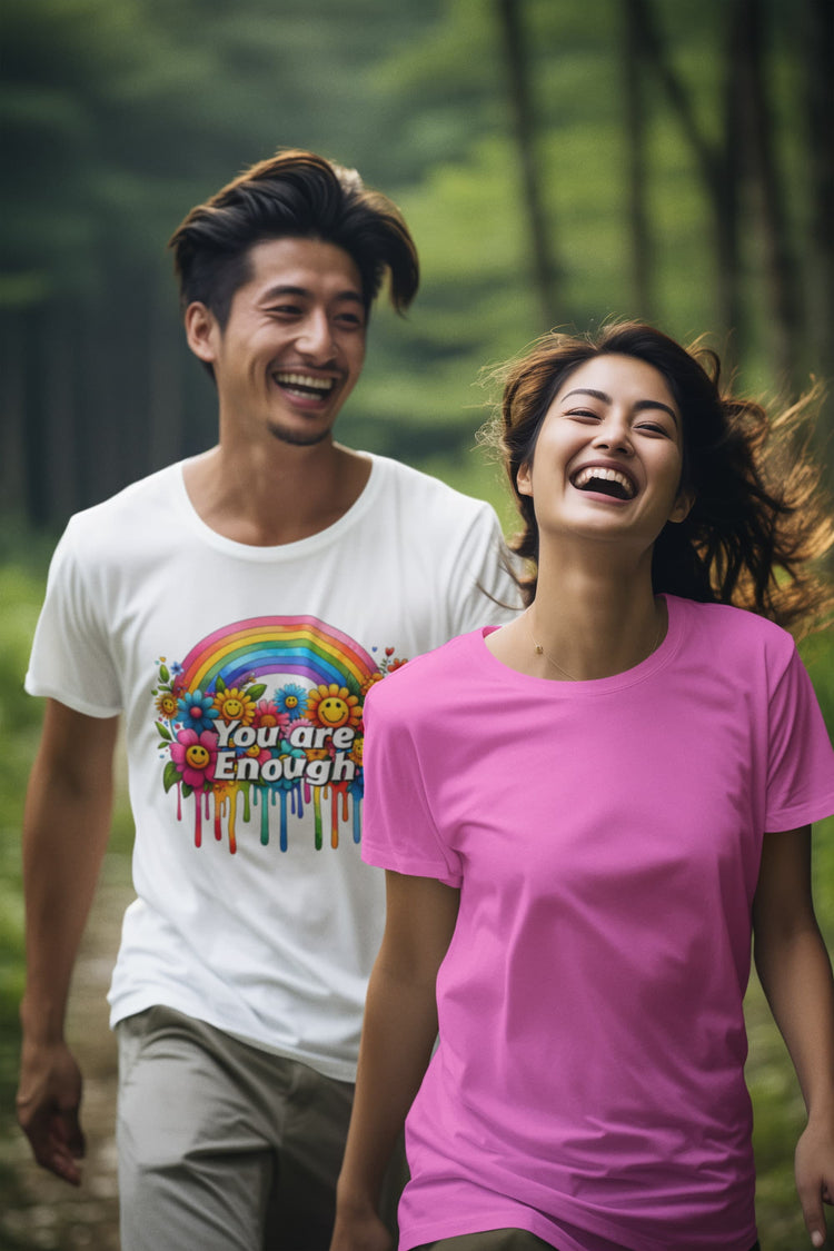 Two people walking outdoors with one wearing a white t-shirt with a colorful design and text, and the other wearing a pink t-shirt.