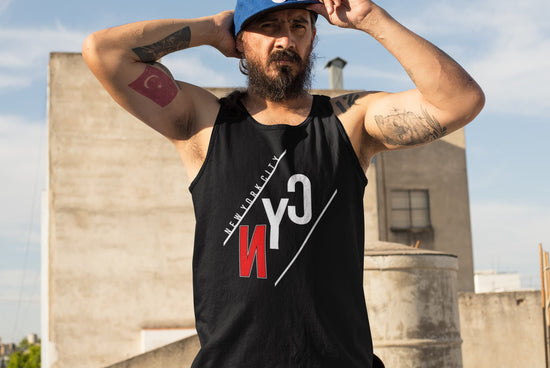 Man wearing a black tank top with a logo, standing on a rooftop with buildings in the background.