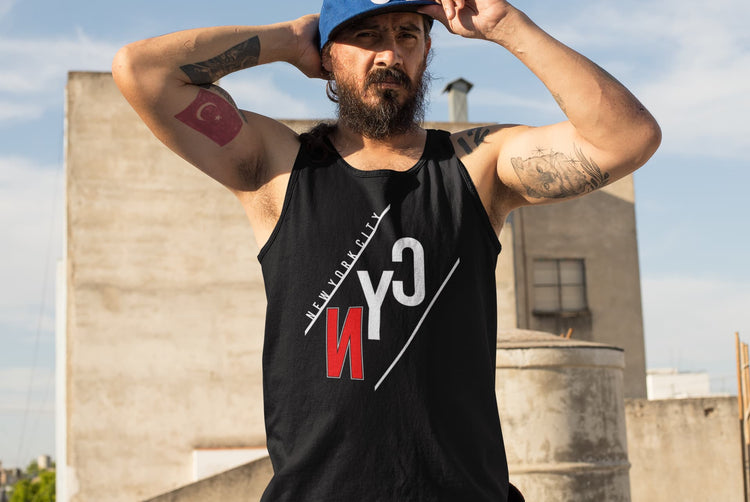 Man wearing a black tank top with a logo, standing on a rooftop with buildings in the background.