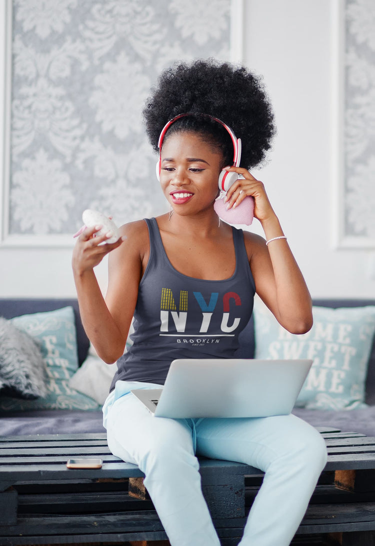 Woman sitting on a couch with a laptop, eating ice cream, and wearing headphones.