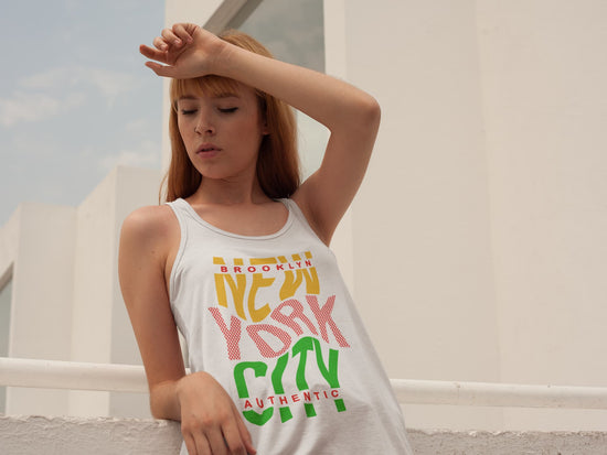 Woman wearing a white tank top with colorful text in an outdoor setting