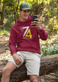 Man in a red hoodie with a number design sitting on a log in a forest