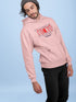 Person wearing a pink hoodie with a graphic design on a light blue background