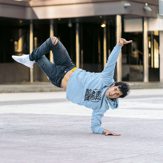 Person in a blue hoodie and jeans performing a handstand on a city street.