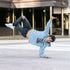 Person in a blue hoodie and jeans performing a handstand on a city street.