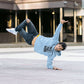 Person in a blue hoodie and jeans performing a handstand on a city street.