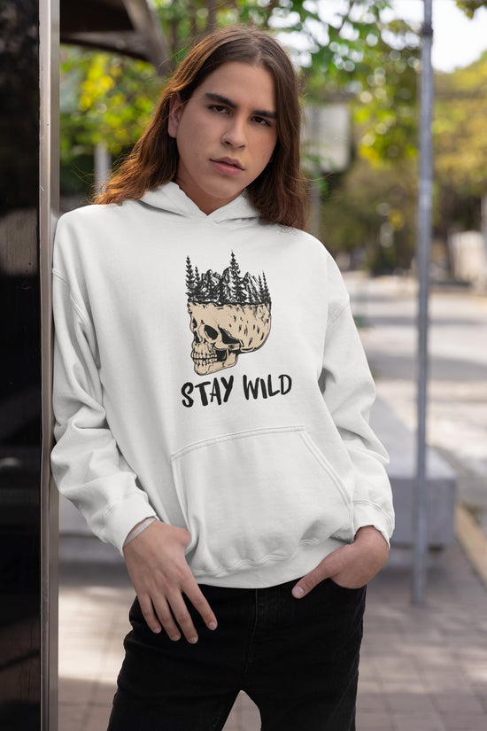 Person wearing a white hoodie with a skull and forest design, standing outdoors.