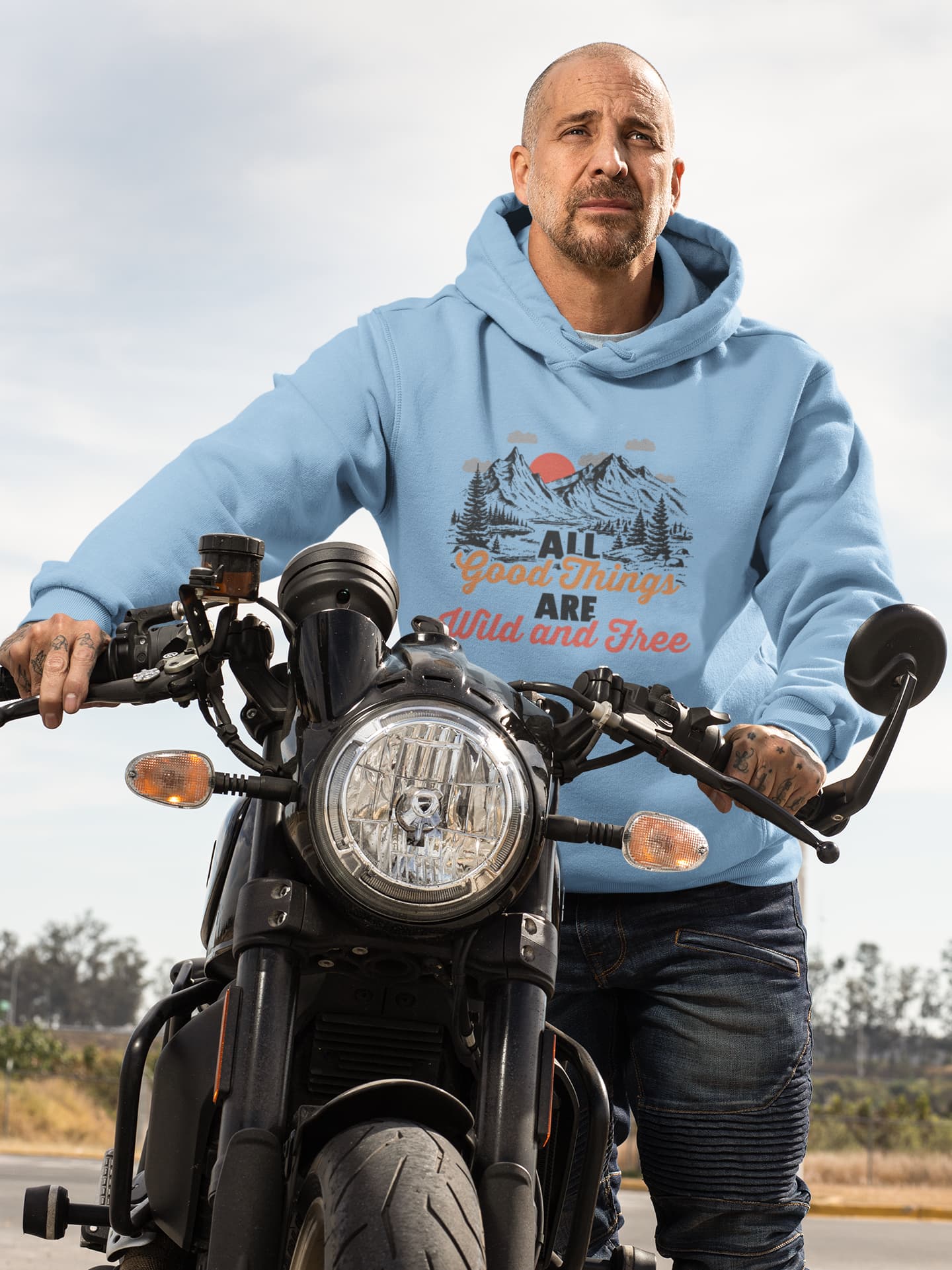 Person wearing a blue hoodie with a graphic design on a motorcycle